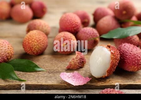 Lychees mûres fraîches avec des feuilles sur une table en bois, en gros plan Banque D'Images