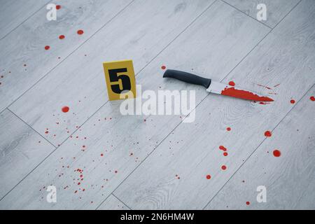 Couteau dans le sang près du marqueur de scène de crime sur un plancher en bois Banque D'Images