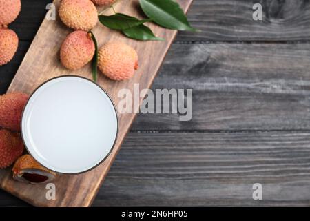 Jus de lychee frais et fruits sur une table en bois noir, plat. Espace pour le texte Banque D'Images