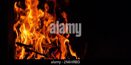 flammes et bois de chauffage brûlant et branches dans une cheminée dans un format de bannière avec flou Banque D'Images