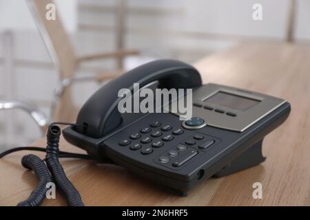 Téléphone de bureau sur table en bois dans le bureau. Service d'assistance téléphonique Banque D'Images