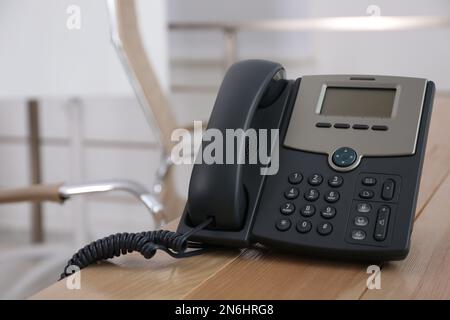 Téléphone de bureau sur table en bois dans le bureau, espace pour le texte. Service d'assistance téléphonique Banque D'Images