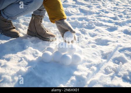 Femme roulant des boules de neige à l'extérieur le jour d'hiver, gros plan Banque D'Images