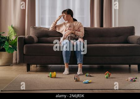Mère célibataire fatiguée souffrant de dépression post-partum. Exténuée femme frustrée tenant son bébé sur les genoux, se sentant stressée avec des nuits sans sommeil et des difficultés stressantes de maternité Banque D'Images