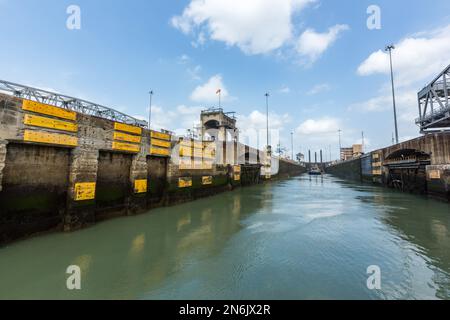 Entrée dans la chambre de l'écluse aux écluses de Miraflores sur le canal de Panama. Un remorqueur et un dredger sont déjà dans la chambre d'écluse. Banque D'Images