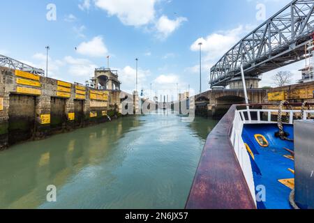 Un bateau d'excursion entre dans la chambre des écluses des écluses de Miraflores sur le canal de Panama. Un remorqueur et un dredger sont déjà dans la chambre d'écluse. Banque D'Images