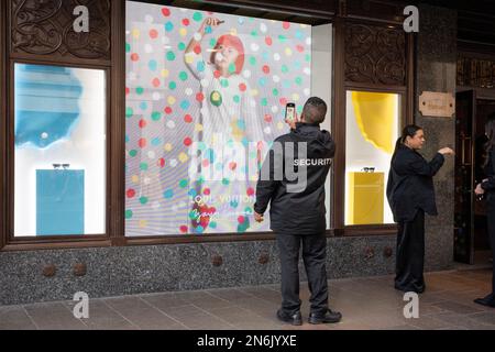 Les membres du public interagissent avec un écran présentant l'artiste Yayoi Kusama dans une fenêtre de Harrods à Knightsbridge, le 9th février 2023, à Londres, en Angleterre. L'artiste inimitable Yayoi Kusama travaille avec Louis Vuitton et leur collaboration est actuellement vue dans les fenêtres de nombreux détaillants qui ont en stock la marque française de bagages et de sacs à main de luxe. Banque D'Images