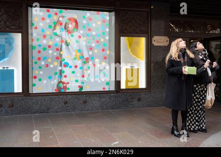 Les membres du public interagissent avec un écran présentant l'artiste Yayoi Kusama dans une fenêtre de Harrods à Knightsbridge, le 9th février 2023, à Londres, en Angleterre. L'artiste inimitable Yayoi Kusama travaille avec Louis Vuitton et leur collaboration est actuellement vue dans les fenêtres de nombreux détaillants qui ont en stock la marque française de bagages et de sacs à main de luxe. Banque D'Images