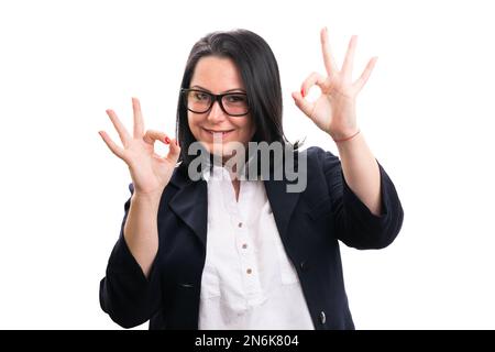 Femme d'affaires amicale souriante comme montrant le double geste acceptable portant un costume élégant et décontracté et des lunettes isolées sur fond blanc Banque D'Images