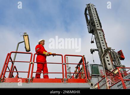 10 février 2023, Brandebourg, Potsdam : Hans-Jürgen Weikert, directeur de la société Drilltec, se dresse devant la tour de forage de 33 mètres de haut sur le site de construction d'énergie géothermique profonde pour la journée portes ouvertes du chantier de construction. Depuis la mi-décembre 2022, des forages sont en cours à Heinrich-Mann-Allee pour le compte de Stadtwerke Potsdam's Energie und Wasser GmbH. Le même jour, les résidents de Potsdam ont pu découvrir l'état actuel des travaux à la journée de construction ouverte. Environ 2000 mètres doivent être forés dans les profondeurs ici. La chaleur géothermique naturelle de doit être utilisée Banque D'Images