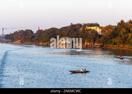 Pêcheurs locaux pêchant avec des filets d'un petit bateau à rames en bois dans la rivière Hooghly, Serampore, près de Calcutta, Bengale-Occidental, Inde en lumière du soir Banque D'Images