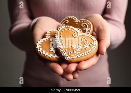 Femme tenant de savoureux biscuits de pain d'épice en forme de coeur, gros plan Banque D'Images