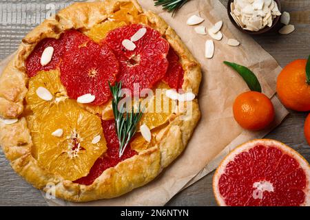 Délicieuse galette aux agrumes, flocons d'amande et romarin sur table en bois, plat Banque D'Images