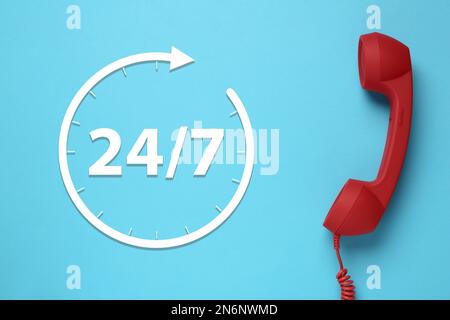 service d'assistance téléphonique 24h/24/7, 7j Combiné rouge sur fond bleu clair, vue du dessus Banque D'Images