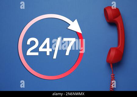 service d'assistance téléphonique 24h/24/7, 7j Combiné rouge sur fond bleu, vue du dessus Banque D'Images