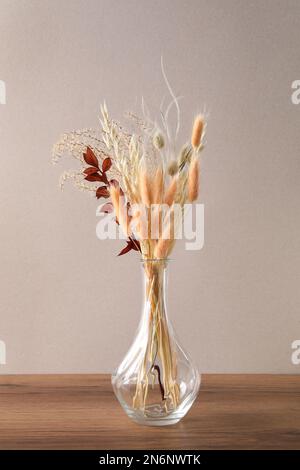 Fleurs séchées dans un vase sur une table en bois sur fond clair Banque D'Images