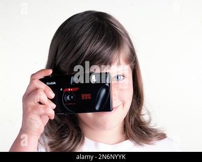 Jeune fille aux yeux bleus tenant un appareil photo Kodak Star 335 35mm vintage Banque D'Images