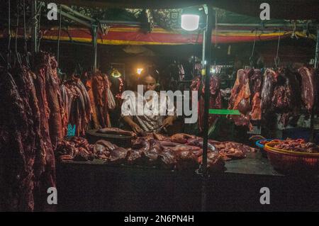 Une boucherie cambodgienne coupe de la viande crue sur le marché principal des légumes et de la viande en gros la nuit. Phsar Dumkor, Phnom Penh, Cambodge. © Kraig Lieb Banque D'Images