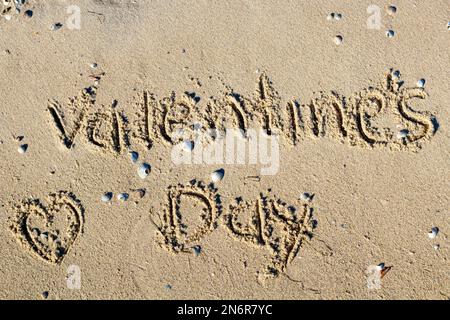 Bonne Saint Valentin écrite sur le sable de la plage tropicale. Banque D'Images
