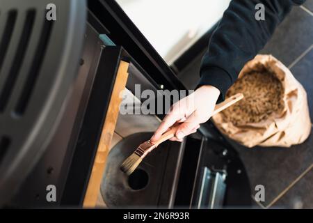 Homme nettoyant poêle à granulés avec brosse Banque D'Images