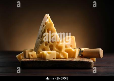 Morceaux de délicieux fromage et couteau sur table en bois Banque D'Images