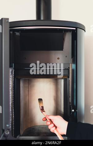 Homme nettoyant poêle à granulés avec brosse Banque D'Images