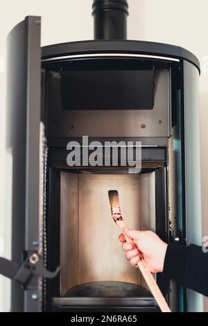 Homme nettoyant poêle à granulés avec brosse Banque D'Images