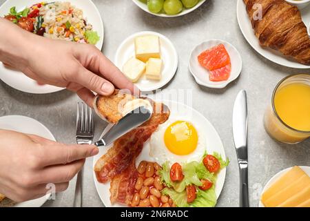 Femme qui répand du beurre sur des toasts à table, gros plan. Service de buffet Banque D'Images