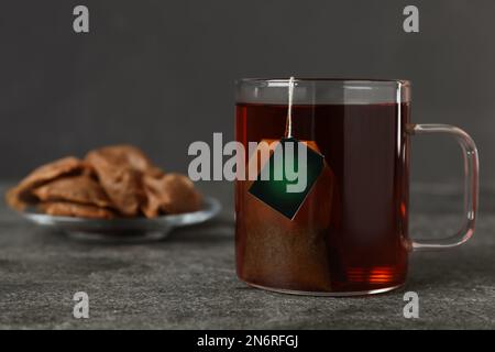 Sachet de thé dans une tasse d'eau chaude sur une table grise. Espace pour le texte Banque D'Images