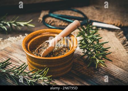 Herbes séchées dans un petit bol et romarin frais sur fond rustique en bois Banque D'Images