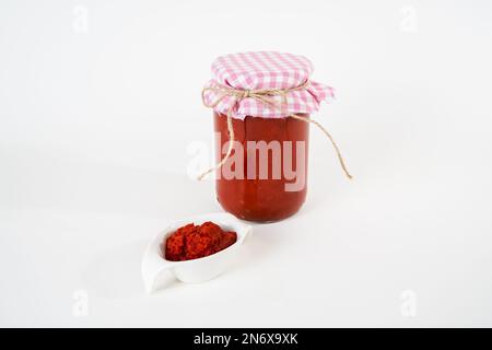 Sauce traditionnelle de tomate au piment maison dans un pot en verre et un petit pot isolé sur fond blanc. Banque D'Images