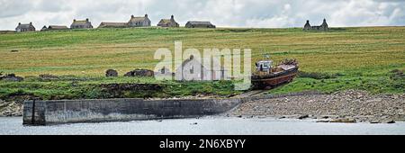 Maisons désertes de croft sur l'île stroma avec un bateau de pêche russitng raillé sur le dérapway abandonné du port Banque D'Images