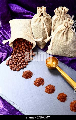 Sacs de Hessian remplis de grains de café torréfiés avec des piles de café fraîchement moulu Banque D'Images