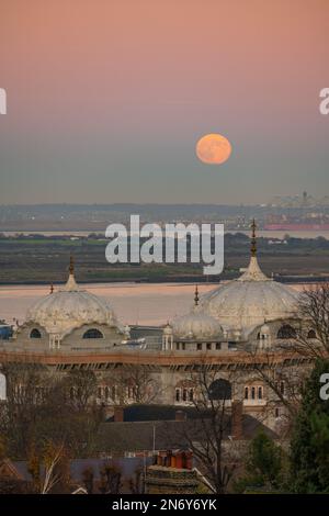 Pleine lune s'élevant au-dessus du DP World London Gateway Port avec le Siri Guru Nanak Darbar Gurdwara à Gravesend de la colline du moulin à vent. Banque D'Images