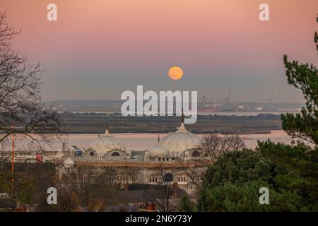 Pleine lune s'élevant au-dessus du DP World London Gateway Port avec le Siri Guru Nanak Darbar Gurdwara à Gravesend de la colline du moulin à vent. Banque D'Images