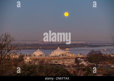 Pleine lune s'élevant au-dessus du DP World London Gateway Port avec le Siri Guru Nanak Darbar Gurdwara à Gravesend de la colline du moulin à vent. Banque D'Images