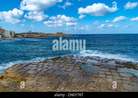 Baie de Qbajjar, Gozo - 13 octobre 2020 : marmites de sel avec la batterie de Qolla l-Bajda en arrière-plan. Banque D'Images