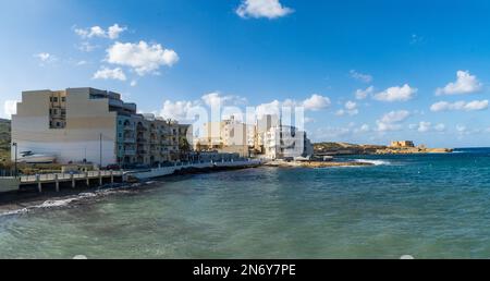 Gozo - 13 octobre 2020: Appartements dans la baie de Qbajjar avec la batterie de Qolla l-Bajda en arrière-plan. Banque D'Images