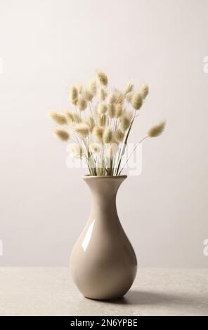 Fleurs séchées dans un vase sur une table sur fond clair Banque D'Images