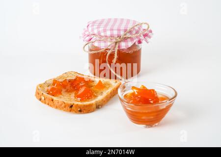 Confiture d'abricot maison, pot, petit bol et une tranche de pain avec confiture isolée sur fond blanc. Banque D'Images