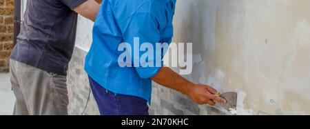 Image de deux ouvriers de la construction de ponçage et de nettoyage d'un mur de moule. Problème d'humidité croissant. Banque D'Images