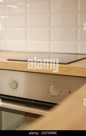 Cuisinière à induction noire moderne, plaque de cuisson intégrée avec dessus en céramique dans la cuisine en bois Banque D'Images