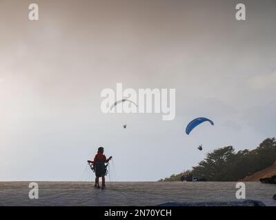 Parapente dans le ciel. Tandem de parapente volant au-dessus de la mer et des montagnes par jour nuageux. Vue sur le parapente et le lagon bleu à Oludeniz, Turquie. spo extrême Banque D'Images