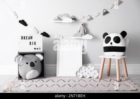 Vider le cadre photo et les jouets mignons près du mur dans la chambre de bébé. Design intérieur Banque D'Images