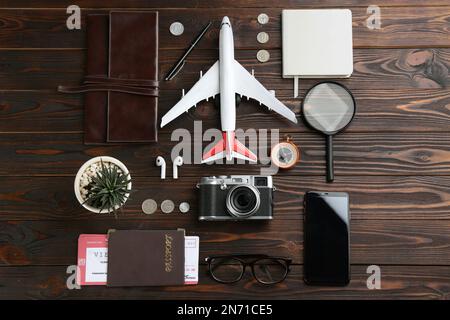 Composition de pose à plat avec avion jouet et articles de voyage sur fond de bois Banque D'Images