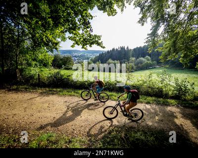 e-motard de montagne sur la route forestière du Luxembourg. Ville de Mersch en arrière-plan. Banque D'Images