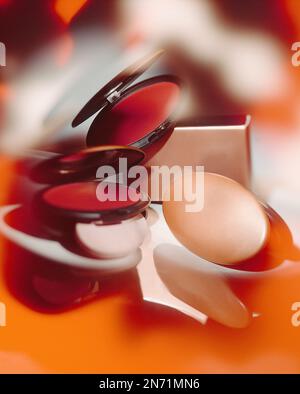 Groupe de boîtiers compacts cosmétiques ovales de marque privée, concept studio encore la vie avec la lumière et les réflexions spectaculaires. La couleur du thème principal est Orange et Rouge. Banque D'Images