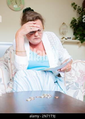 Retraite : coût de la vie. Une dame âgée frustrée par la hausse du coût de ses factures domestiques. À partir d'une série d'images associées. Banque D'Images