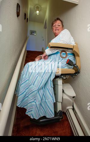 Retraite : ascenseur d'escalier. Une femme âgée utilisant une aide à la mobilité domestique sur les escaliers jusqu'à sa maison. À partir d'une série d'images associées. Banque D'Images