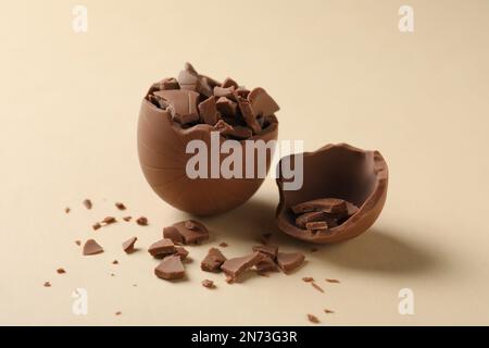 Œuf au chocolat au lait cassé sur fond beige Banque D'Images